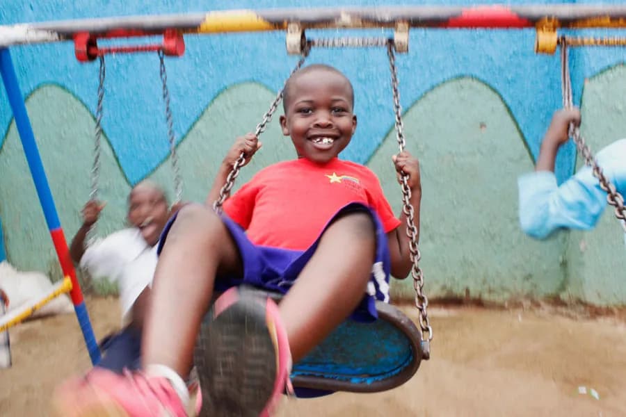 A boy on a swing at Little Light Children Center in Namuwongo, Kampala
